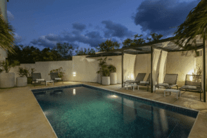 Una piscina iluminada en el patio trasero del hotel durante la noche, creando un ambiente relajante y acogedor.